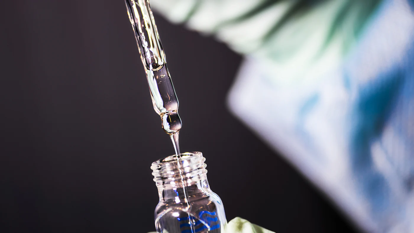 A pipette dripping liquid into a small glass vial in a lab