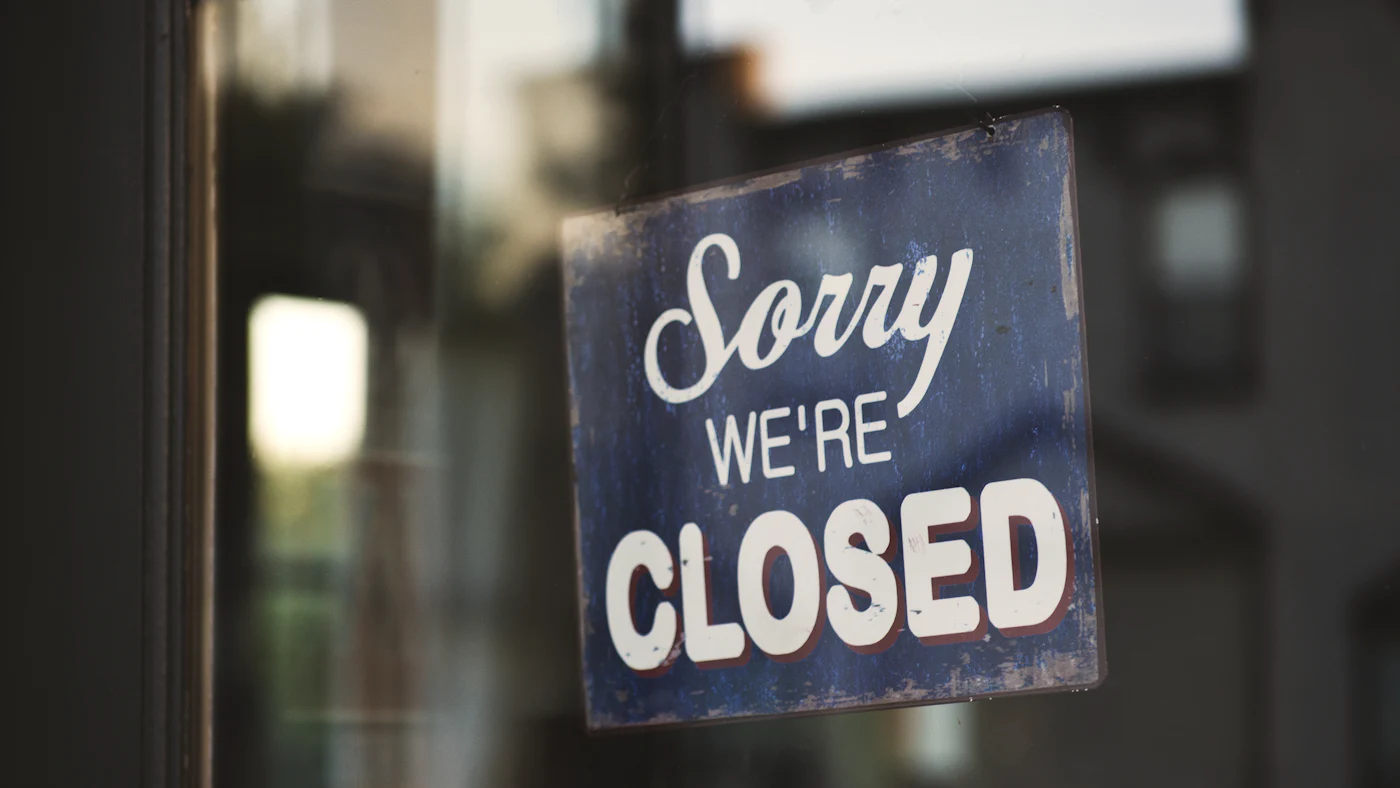 A “Sorry, we’re closed” sign hanging in a shop door